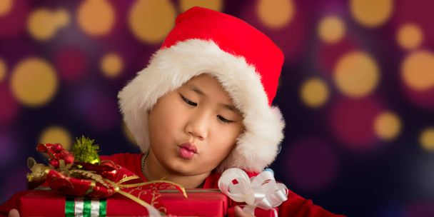クリスマスの日の概念は、子供たちが暗い背景のボケに対してサンタクロスから受け取ったギフトです。. - 写真・画像