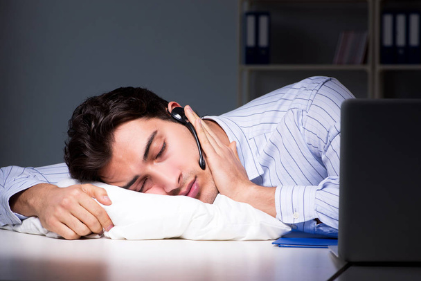 Κουρασμένος και εξαντλημένος χειριστής γραφείου βοήθειας κατά τη νυχτερινή βάρδια - Φωτογραφία, εικόνα