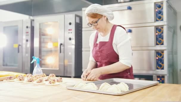 Mujer en vasos y delantal hornea pasteles en la panadería
 - Imágenes, Vídeo