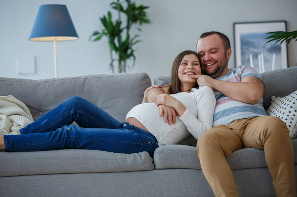 Picture of happy married couple on gray sofa - Fotografie, Obrázek