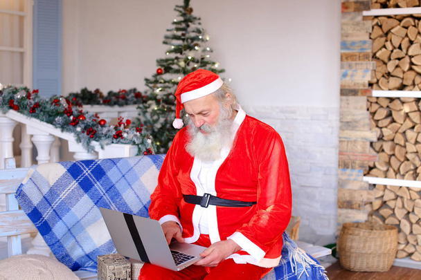 Gracieux Père Noël travaillant sur ordinateur portable
. - Photo, image