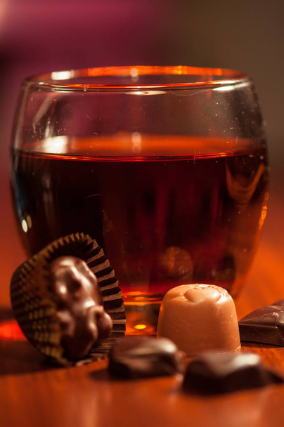 Whiskey en chocolade. Een glas whiskey op een rustieke tafel met chocolade - Foto, afbeelding