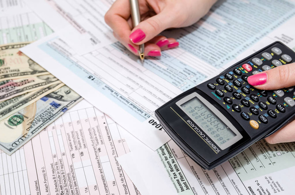 mujer de negocios con pluma y calculadora en el formulario fiscal 1040
 - Foto, Imagen