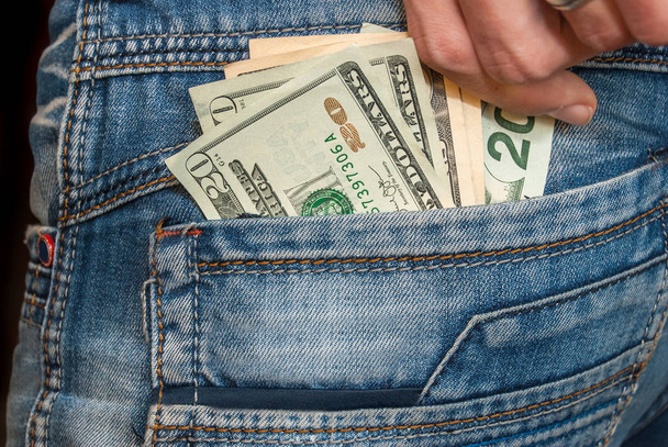 Mão masculina com dólares no bolso
 - Foto, Imagem