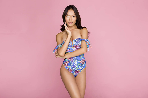 美しく、セクシーなアジアの女の子色水着ビキニの写真広告、スタイル流行の smiling.perfect、ピンクの背景の上に立って - 写真・画像