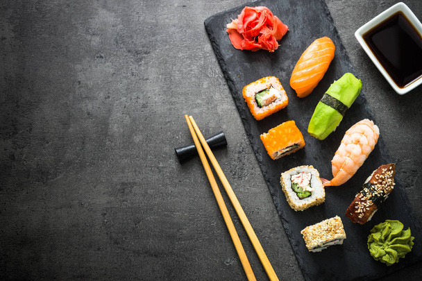 Sushi en sushi roll set op zwarte stenen tafel bovenaanzicht - Foto, afbeelding