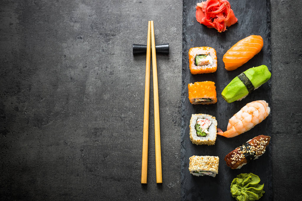 Sushi en sushi roll set op zwarte stenen tafel bovenaanzicht - Foto, afbeelding
