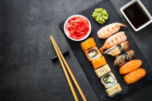 Rolo de sushi e suhi definido na vista superior da mesa de pedra preta
 - Foto, Imagem