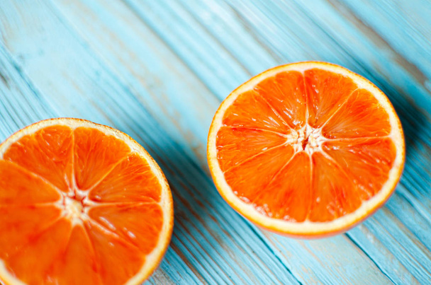青い木製の背景にオレンジをスライス  - 写真・画像