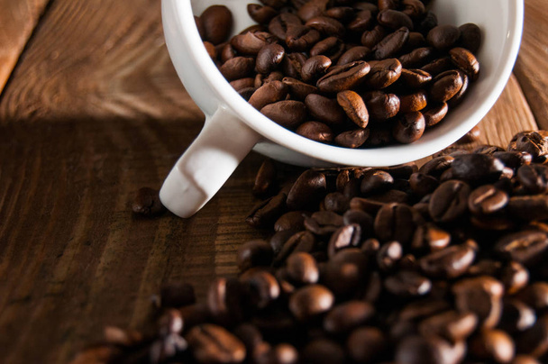 Close-up of half a cup of coffee beans. A part is scattered - Foto, Imagem