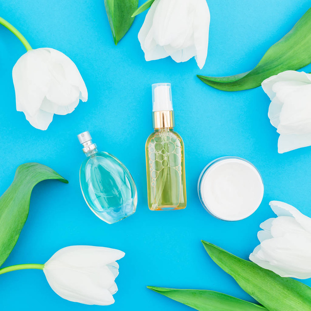 Draufsicht auf verschiedene Kosmetikprodukte mit Tulpen auf lebendigem Hintergrund - Foto, Bild