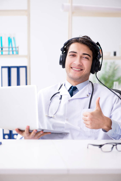 Чоловік лікар, який слухає пацієнта під час сеансу телемедицини
 - Фото, зображення