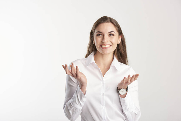 Portrait of happy young businesswoman wearing white shirt while standing with her arms raised and wondering. Isolated on white background.  - Fotografie, Obrázek