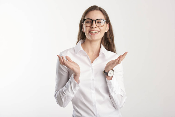 Porträt einer glücklichen jungen Geschäftsfrau, die weißes Hemd trägt, während sie mit erhobenen Armen steht und sich wundert. isoliert auf weißem Hintergrund.  - Foto, Bild