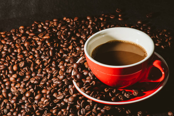 кава в червоній чашці і кавові зерна є фоном
. - Фото, зображення