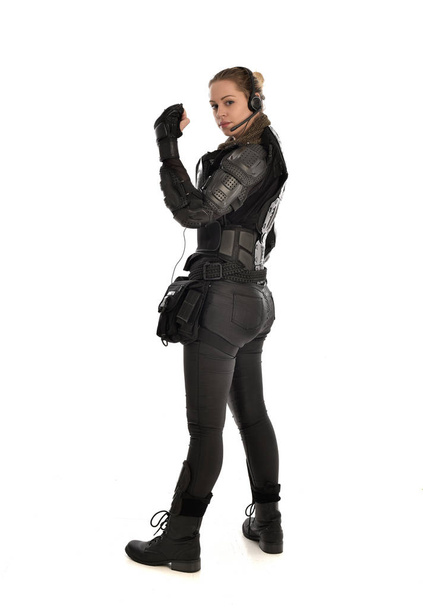 portrait complet de soldat féminin portant une armure tactique noire face à la caméra, isolé sur fond de studio blanc
. - Photo, image