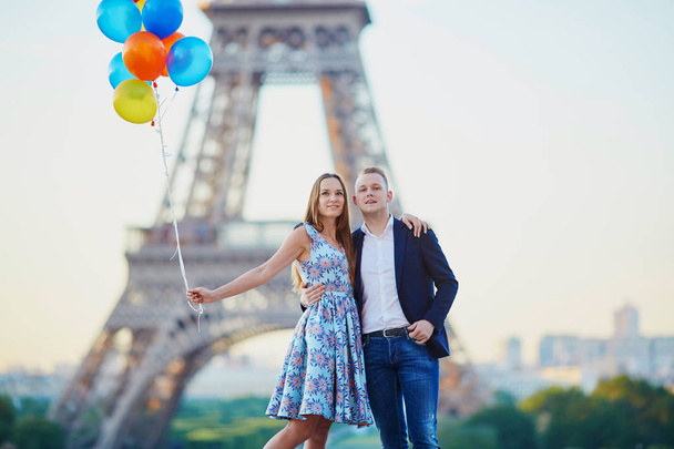 Loving couple with bunch of colorful balloons kissing near the Eiffel tower in Paris, France - Foto, imagen