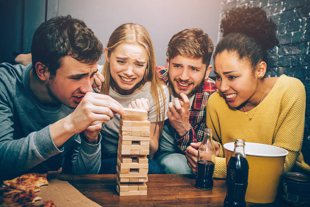 Four groupmates playing jenga game. The game is intensive and hard. Seems like this pieces of towel will fall down very soon because of the guy on the left. - Фото, зображення