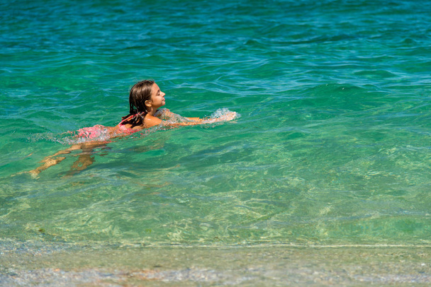 Tyttö pitää hauskaa uiminen mereen ja roiskuu vettä
 - Valokuva, kuva
