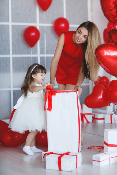 Beauty Valentine's Day Woman with red balloons. Fashion Model Girl face profile Portrait with red balloons in the shape of heart in her hand. Red Lips and Nails. Pink blurred background. Beautiful Luxury Makeup and Manicure, hair. - Фото, изображение