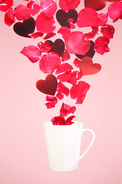 Αιωρούμενο κούπα καφέ με πιτσιλιές από ροδοπέταλα και καρδιές. S - Φωτογραφία, εικόνα