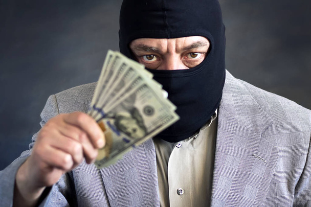 Businessman in balaclava with dololors in hands on dark background. Crime. Theft. - Foto, Imagem