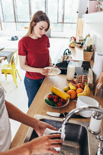 Kaksi tyttöä ystäviä keittiössä valmistelee aamiaista ruoanlaitto ja tiskaus
 - Valokuva, kuva