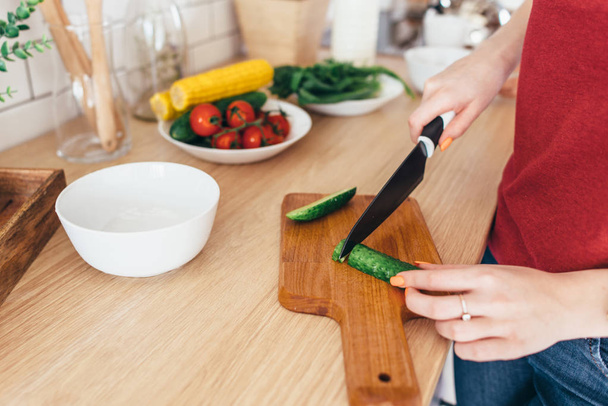 Woman cutting vegetables on the wooden board - Foto, Bild