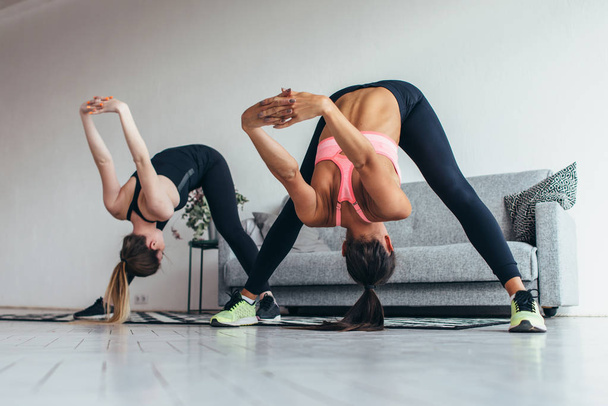 Fitness women back stretching training at home. Young slim girl makes forward bend - 写真・画像