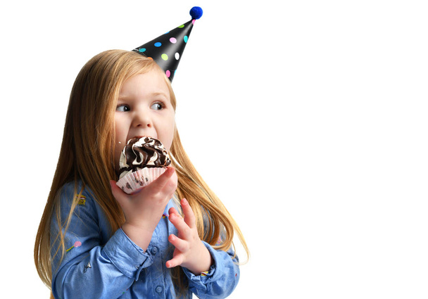 Three years girl kid eat sweet chocolate cake celebrating in birthday cap isolated  - Foto, Bild