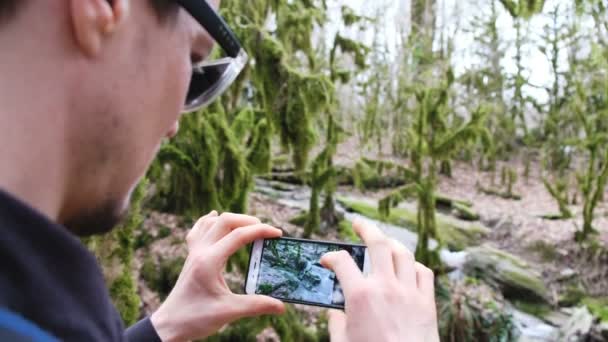 Egy férfi szemüveg fényképek egy patak, az erdő egy okostelefon, 4k. - Felvétel, videó