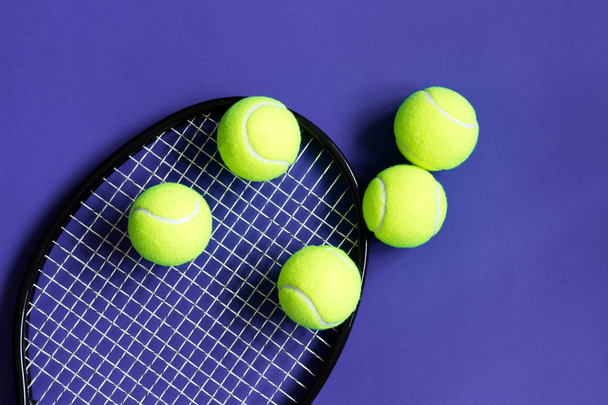 Tennisballen op zwarte racket. Violette achtergrond. Concept sport. - Foto, afbeelding