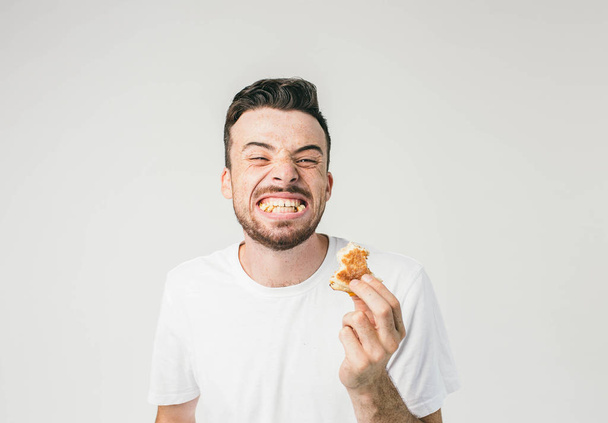 An interesting picture of a man showing his teeth full of pieces of bread from burger. He is so happy to eat it that he wanted to share this happiness with everybody. Cut view. - Photo, image