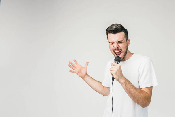Nice picture of an emotional guy singing in microphone. His trying to do his best and reaches the highest note in the song. Cut view. - Foto, immagini