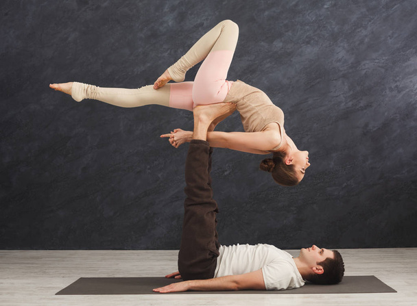 Young couple practicing acroyoga on mat together - 写真・画像