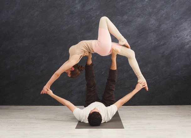 Young couple practicing acroyoga on mat together - Photo, Image