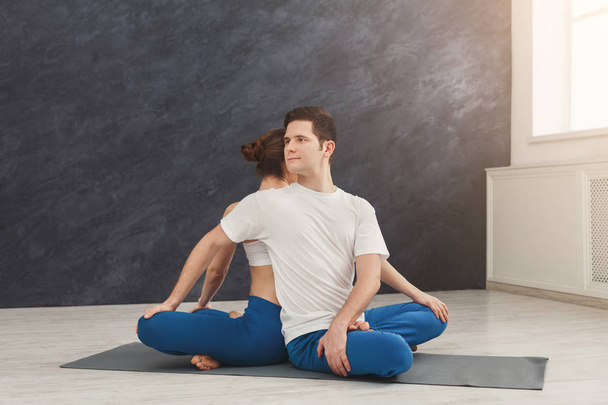 Pareja joven practicando yoga juntos en estudio
 - Foto, Imagen
