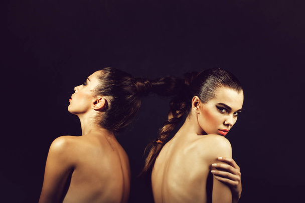 naked lesbian models, sexy women or pretty girls, with braided or tied, beautiful, healthy, brunette, long hair into braid or plait on black background. Friendship and love - Φωτογραφία, εικόνα