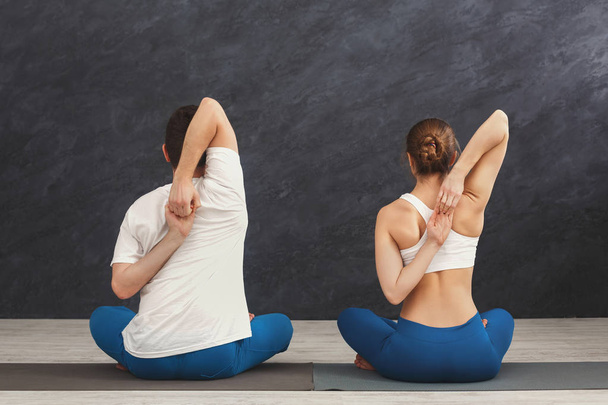 Young couple in yoga class, back stretching - Valokuva, kuva