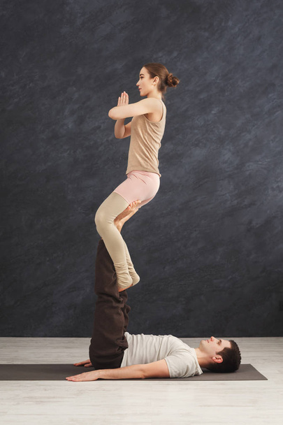 Young couple practicing acroyoga on mat together - Fotó, kép