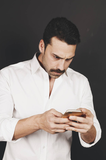 Mladý pohledný muž používající mobilní telefon s negativní postoj - Fotografie, Obrázek