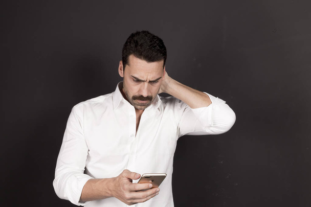 Young handsome man using a mobile phone with a negative attitude - Φωτογραφία, εικόνα