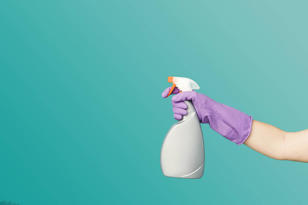 Een hand in de handschoen holding spray van reinigingsvloeistof - Foto, afbeelding
