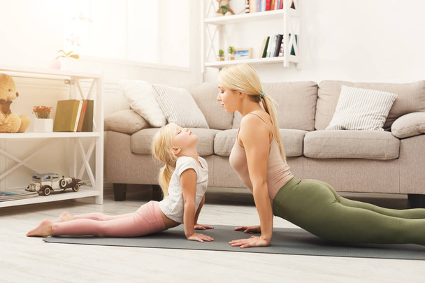 Mother and daughter doing yoga exercises at home - Photo, image