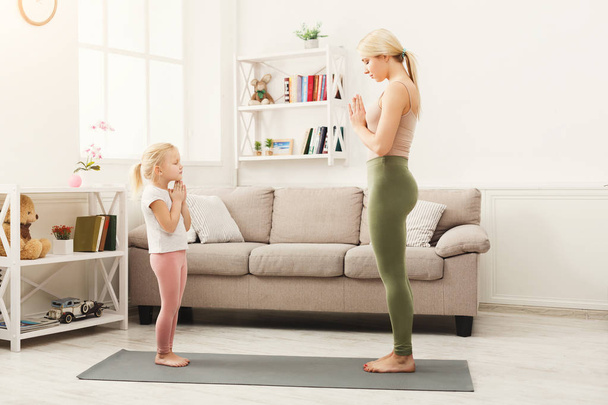 Mother and daughter doing yoga exercises at home - Photo, Image