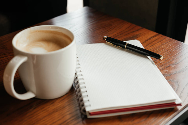top view. coffee cup with coffee. pen putting on blank notebook. - Foto, Imagen