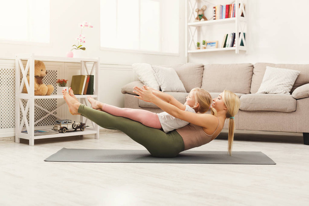 Mother and daughter doing yoga exercises at home - Foto, Bild