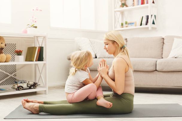Happy mother and daughter hugging while home yoga class - Foto, afbeelding