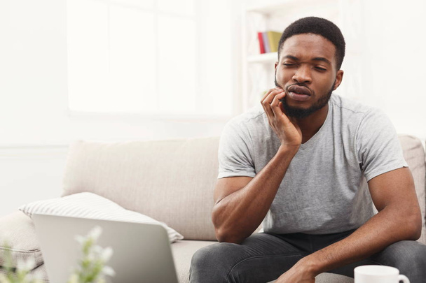Young african-american man having toothache at home - Foto, Imagem