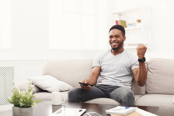 Щасливий чоловік дивиться телевізор за допомогою пульта дистанційного керування у вітальні
 - Фото, зображення